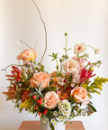 Wide shot of “The Grand Gesture” luxury Valentine’s Day arrangement with peach roses, pink focal flowers, and textured greenery, designed for Boulder CO flower delivery.