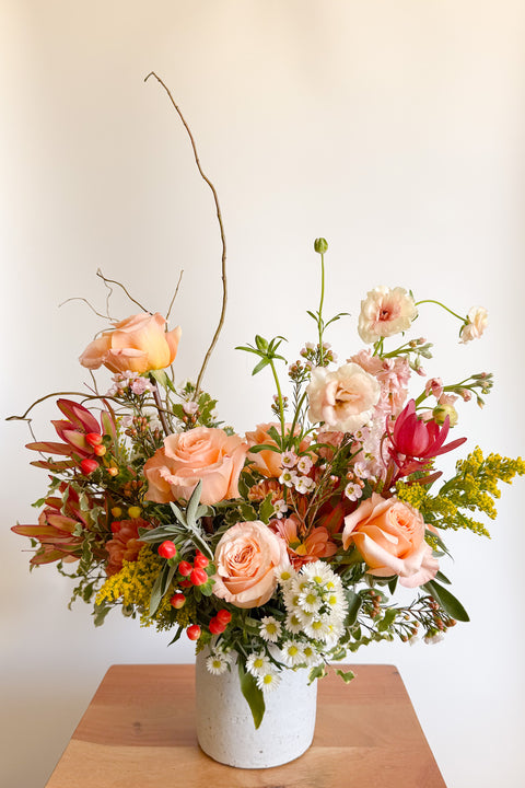 Wide shot of “The Grand Gesture” luxury Valentine’s Day arrangement with peach roses, pink focal flowers, and textured greenery, designed for Boulder CO flower delivery.