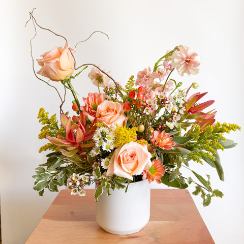 Close-up of “The Flirty Little Number” Valentine’s Day flowers arranged in a modern white vase, designed by Arianna Floral Design with peach roses, pink accents, and textured greenery in Boulder CO.