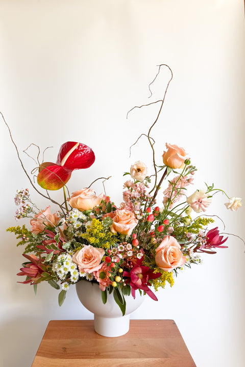 Wide shot of “The Grand Gesture” luxury Valentine’s Day arrangement with peach roses, pink focal flowers, and textured greenery, designed for Boulder CO flower delivery.